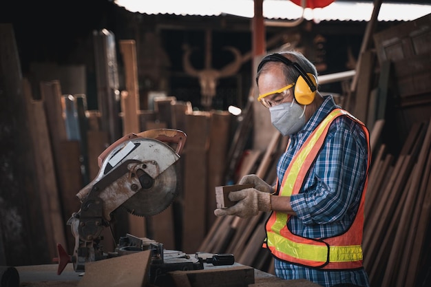 An elderly carpenter works the wood with meticulous care