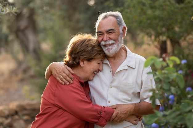 Elderly couple holding each other romantically at their countryside home garden