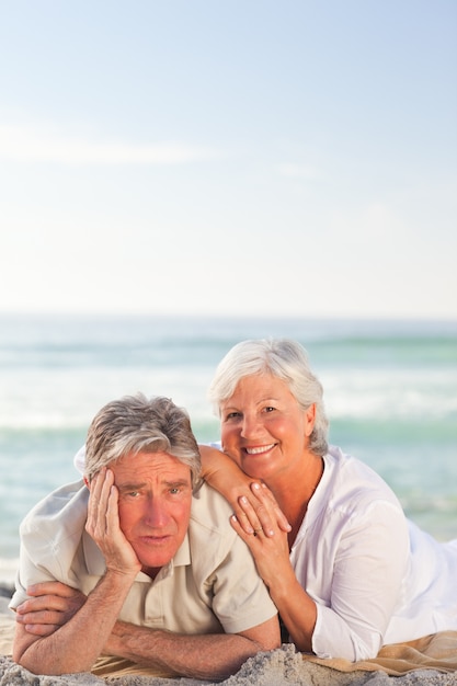 Elderly couple lying down on the beach