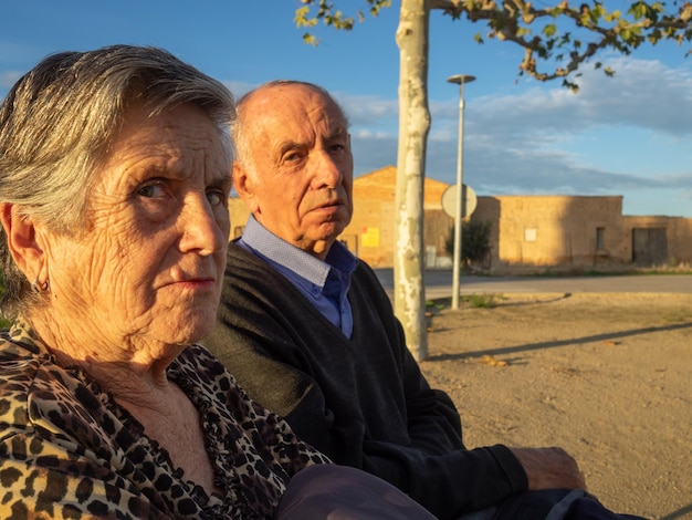 Elderly couple sitting on bench with angry and stern look