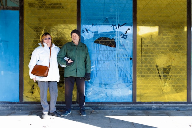 Elderly couple standing together in a devastated city