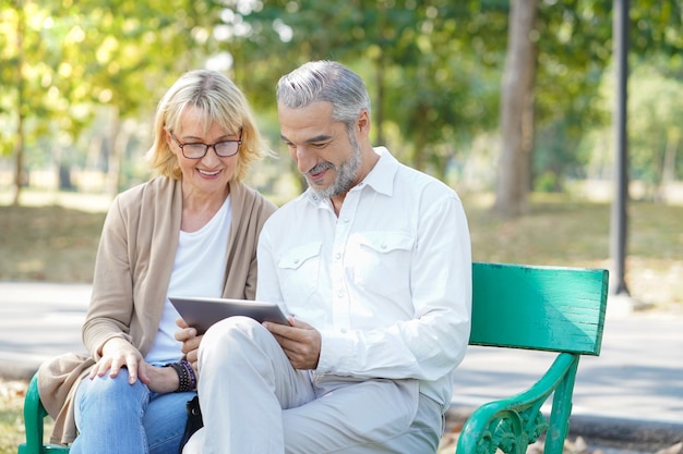 Elderly couple using a tablet in the park