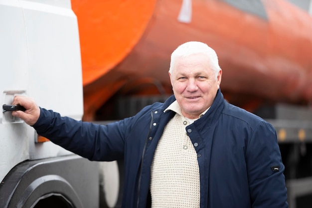 An elderly driver at the cab of a large truck