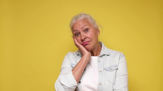 An elderly European woman with a sad expression experiences discomfort and sorrow Studio shot