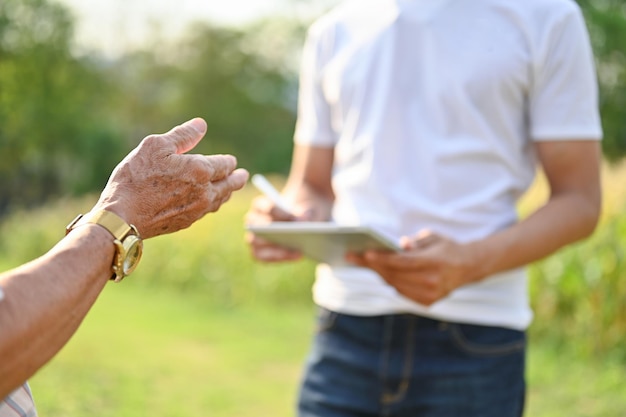 An elderly farmer talking and working with his supplier in a cornfield