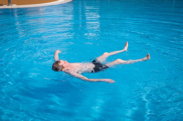 An elderly grayhaired retired man swims in the pool The concept of a healthy active lifestyle