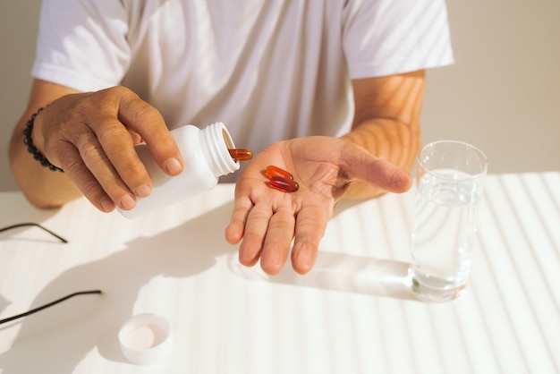 Elderly ill man with pills in hands.