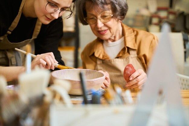 Photo elderly lady learns to work with clay in ceramics studio