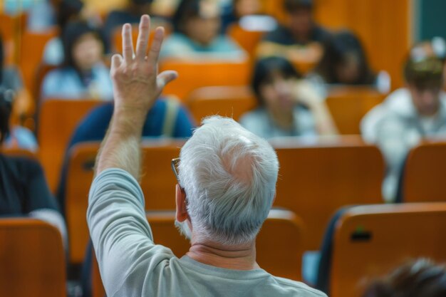 Elderly man actively participating in a classroom setting raising his hand to ask a question among younger students