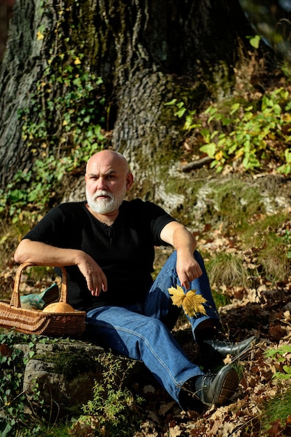 Elderly man in autumn park with fall foliage.