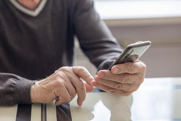 Elderly man dials number in smartphone from home