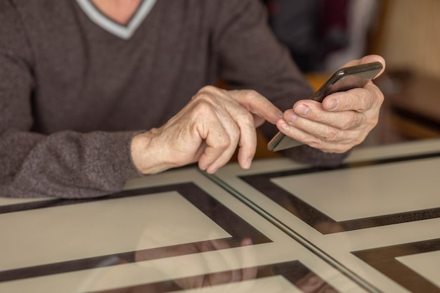 Elderly man dials number in smartphone from home