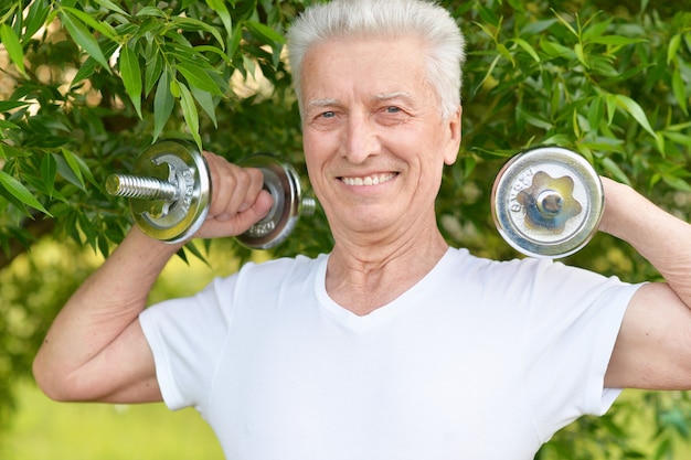 Elderly man exercising with dumbbells in  park