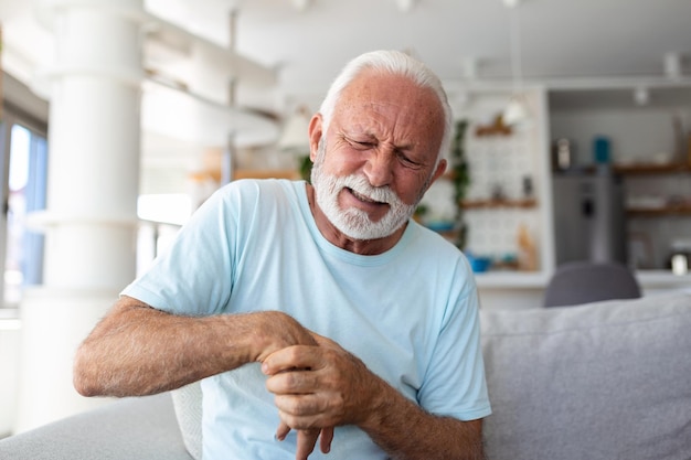 Elderly man has pain in fingers and hands Old man with finger pain Man massaging his arthritic hand and wrist