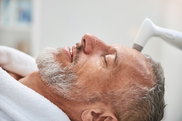 an elderly man having facial skin treatment at a salon