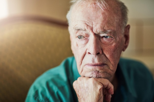 Photo elderly man and sad with thinking of memory in retirement home with remember nostalgia or reflection on sofa senior person and lonely with alzheimers depression and thoughtful on couch in lounge