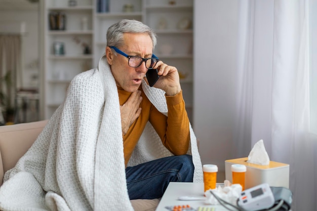 Elderly man sick at home covered with blanket