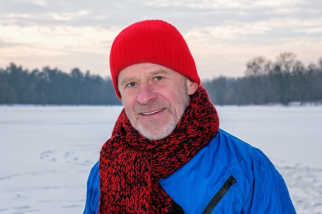 Elderly man standing in winter forest, resting after exercise