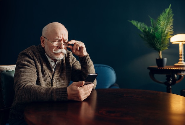 Elderly man using mobile phone in home office