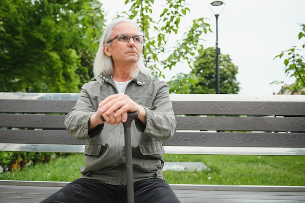 Elderly man walks with a cane in a city spring park