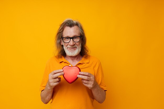 Elderly man in yellow glasses with a gray beard Red heart monochrome shot