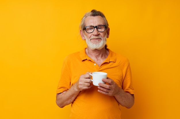 Elderly man in a yellow tshirt white mug yellow background