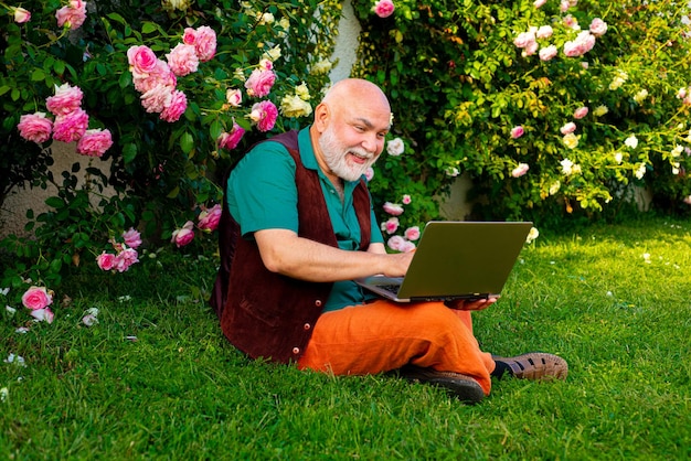 Elderly pensioner enjoy his retirement happy senior in using laptop on backyard retirement lifestyle