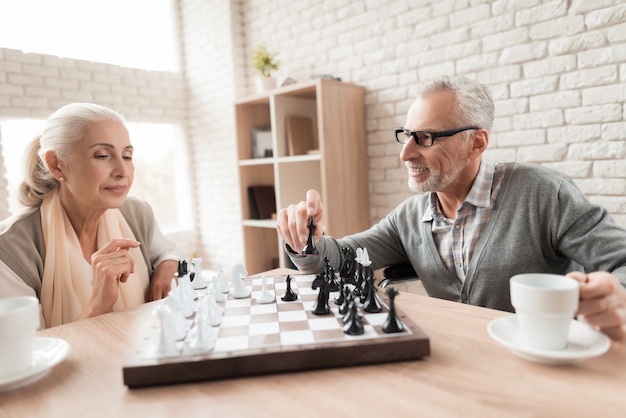 Elderly people play chess in nursing home.