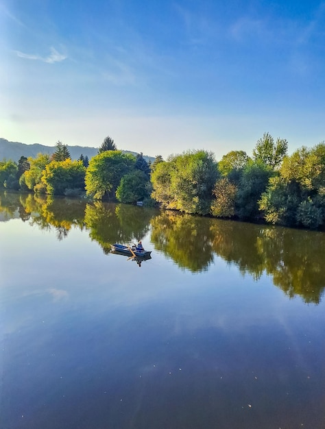 Elderly person in hoodie sitting relaxing on fishing boat at autumn weather