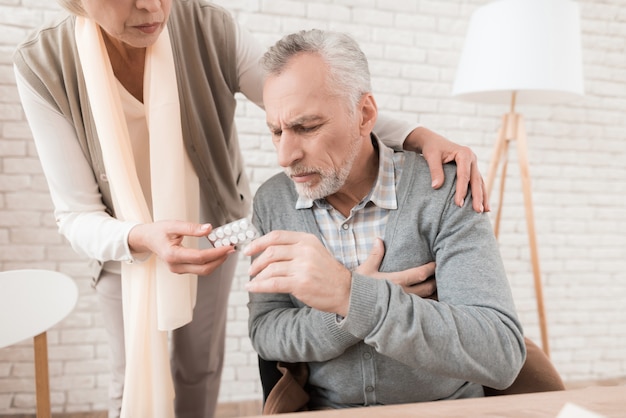 Elderly wife gives pills to sick old husband.