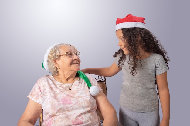 Elderly woman and child with Christmas hat on gray