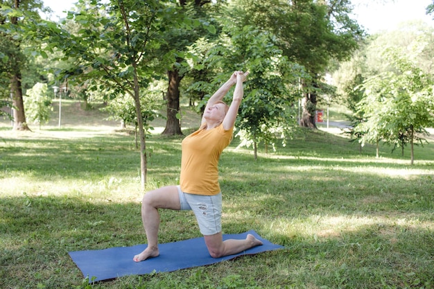 An elderly woman does yoga in the park to perform stretching for balance and balance