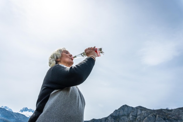 An elderly woman drinking water at Lake Ercina in the Lakes of Covadonga Asturias Spain