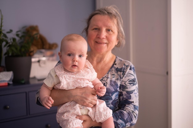 Elderly woman grandmother holding a month baby in her arms