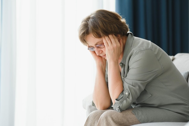 An elderly woman has headaches she touches her head with her hands reports symptoms of dizziness migraines