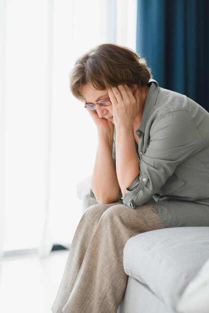 An elderly woman has headaches she touches her head with her hands reports symptoms of dizziness migraines