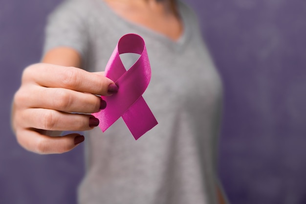 Elderly woman holding purple ribbon awareness w copy space. Symbol is used to raise awareness for Alzheimer's disease, elder abuse, epilepsy, pancreatic cancer, thyroid cancer and lupus. Close up.