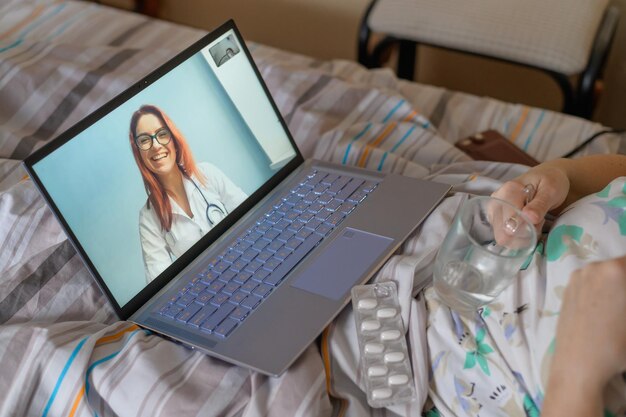 Photo an elderly woman is sick with coronavirus and is in quarantine a pensioner lies in bed and consults a doctor online about a viral disease