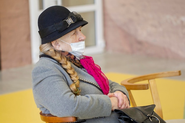 An elderly woman in a medical mask is not looking at the camera