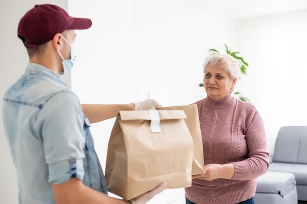 An elderly woman in a medical mask stays at home. Food delivery to the elderly.