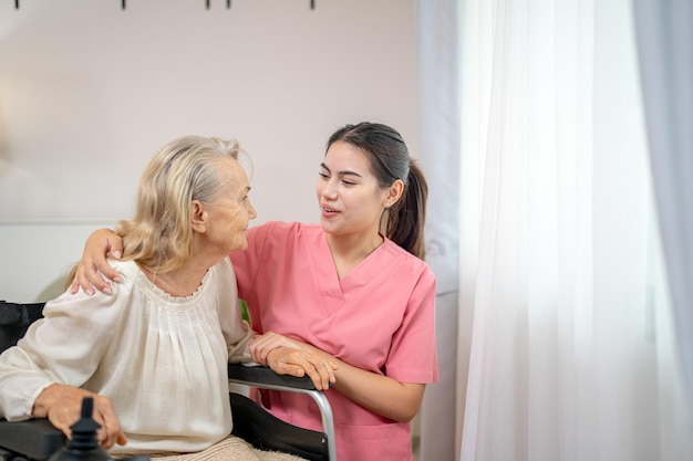 Elderly woman and nurse at home Healthcare worker girl cares about senior female person indoors