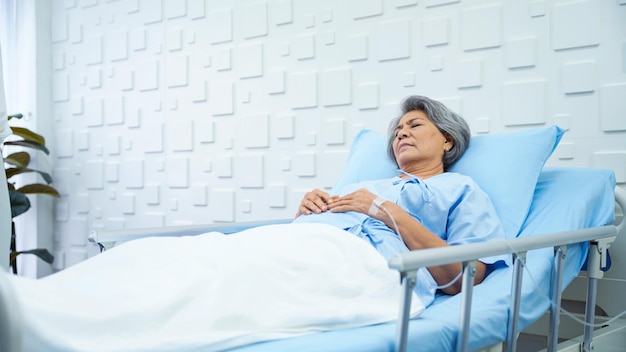 Elderly woman patient lying in bed receiving saline in the patient room Tired from the symptoms of the disease