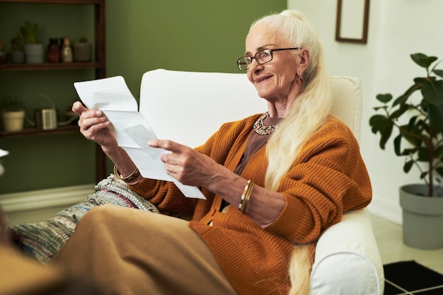 Elderly woman reading document in cozy living room