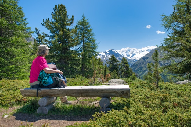 An elderly woman rests during an alpine trek