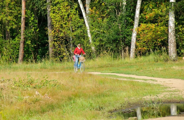 An elderly woman rides a Bicycle on a forest road