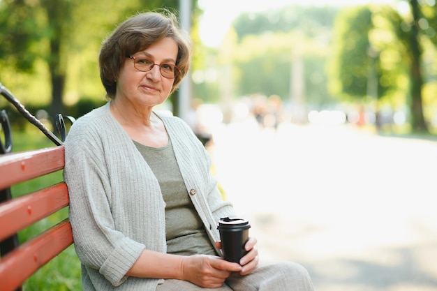 Elderly woman sitting and relaxing on a bench outdoors in park