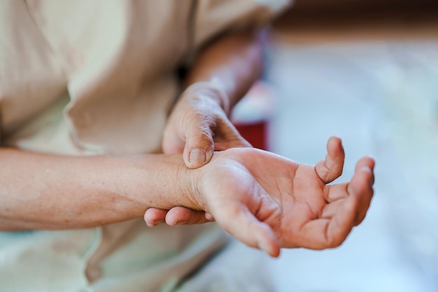 An elderly woman squeezing her wrist due to pain Concept of health problems in the elderly