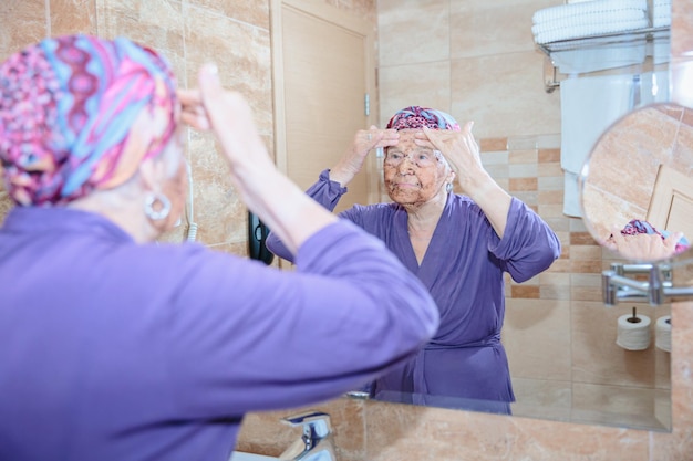 Photo elderly woman taking care of her face