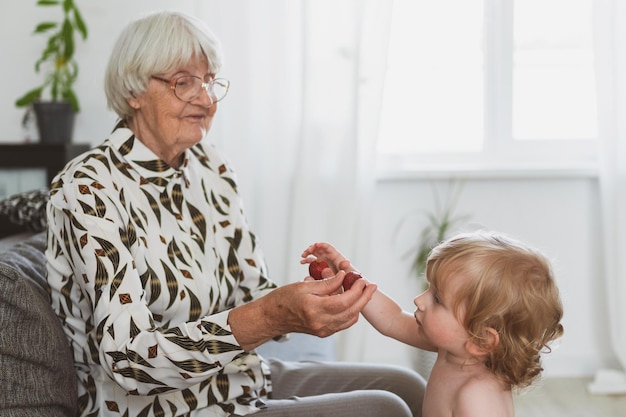 Elderly woman treats her little grandson to strawberries