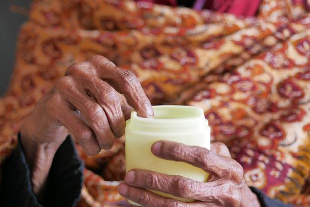 Elderly woman using petroleum jelly onto skin